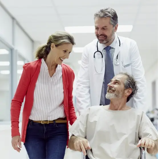 Doctor Pushing Patient in Wheelchair with Women Walking Alongside