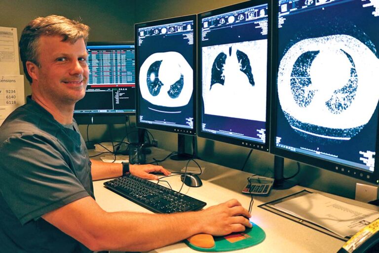 Man reviewing lung scan images on 3 computer screens
