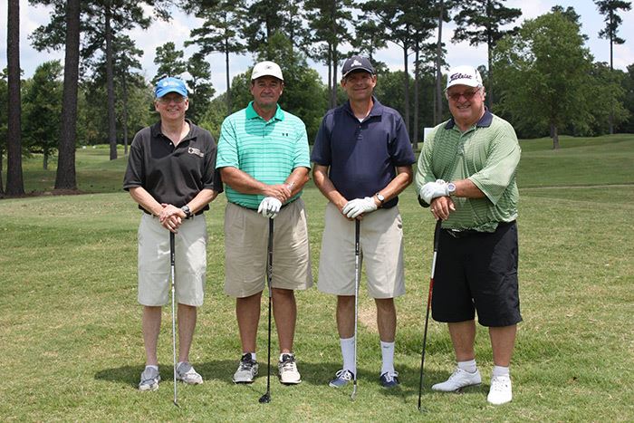 4 people posing with gold clubs on a course