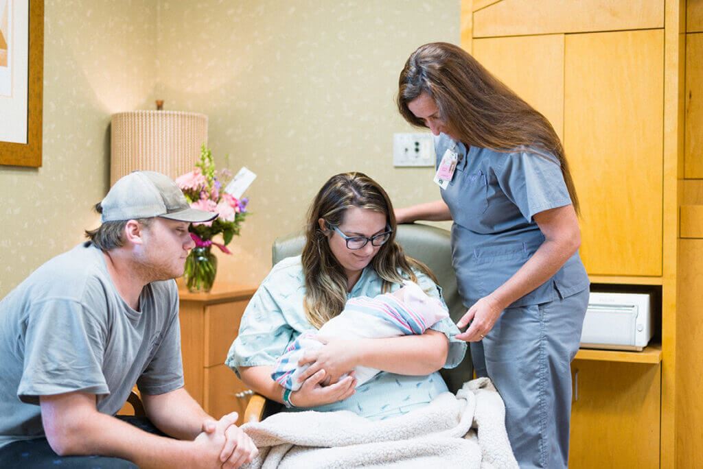 man and woman with a newborn baby and a nurse